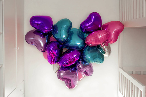 Des ballons en aluminium suspendus au mur dans une pièce en forme de cœur le jour de la Saint-Valentin. Décoration festive de l'appartement. - Photo, image