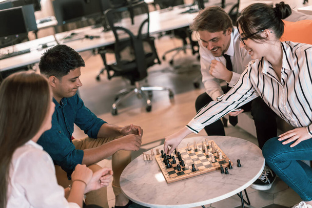 Multiethnic group of businesspeople playing chess while having a break in relaxation area at modern startup office. High-quality photo - Foto, Imagem