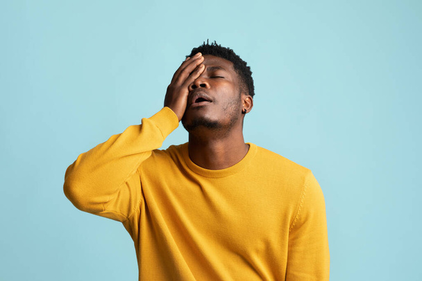 Exhausted black guy touching his face, blue background - Φωτογραφία, εικόνα