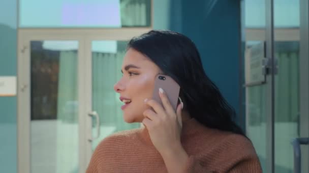 Latin kökenli genç bir kadın sokak arkası ofis binasında yürüyor cep telefonuyla konuşuyor arkadaşça sohbet ediyor servis ya da taksi çağırıyor telefon görüşmelerine cevap veriyor. - Video, Çekim
