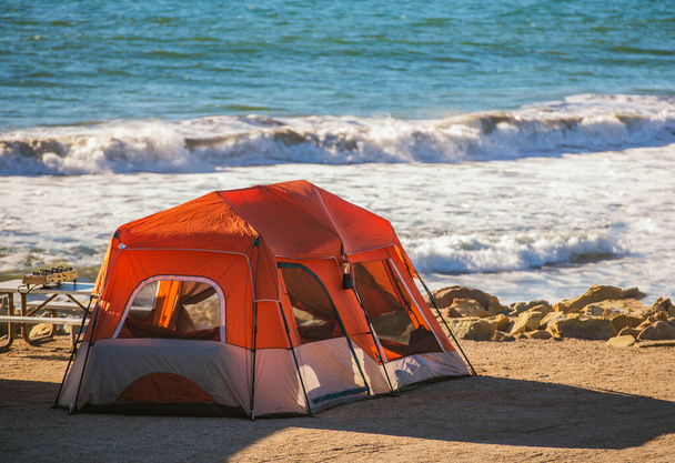 Namiot Camping na Wybrzeżu Oceanu. Duży nowoczesny namiot i linia wodna tuż za nim. Temat wakacji na kempingu nadmorskim. - Zdjęcie, obraz