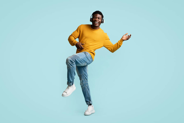 Carefree young black guy with wireless headset dancing - Фото, зображення