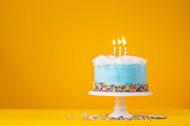 黄色の背景に3つのキャンドルブルーの誕生日ケーキ - 写真・画像