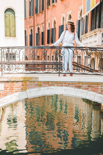 young pretty woman traveler standing at venice bridge cross canal gondolas in water - 写真・画像