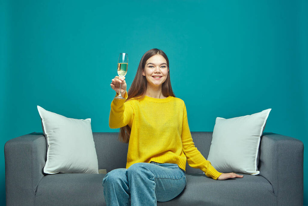 Smiling friendly sociable girl raised champagne glass enjoying holiday party celebrating womens day sitting on couch - Photo, Image