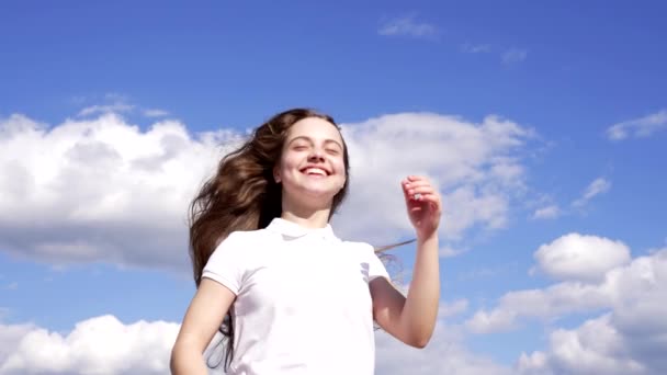 χαρούμενο παιδί απόλαυσε τον ήλιο και τον άνεμο με μακριά μαλλιά στο φόντο του ουρανού, απόλαυση - Πλάνα, βίντεο