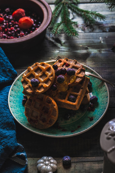Croissant Waffle or Croffle with srawberry and blueberry sauce served in plate and dark background. Close up, copy space. - Foto, Bild