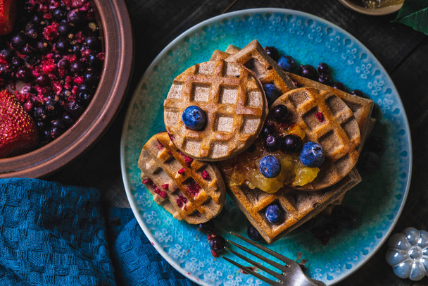 Croissant Waffle or Croffle with srawberry and blueberry sauce served in plate and dark background. Close up, copy space. - Photo, Image