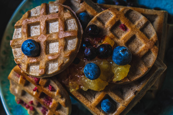 Croissant Waffle or Croffle with srawberry and blueberry sauce served in plate and dark background. Close up, copy space. - Φωτογραφία, εικόνα