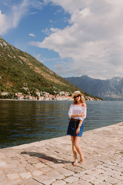 Lady on the island in The Bay of Kotor, the Adriatic Sea in southwestern Montenegro. Its well-preserved group of medieval towns. Travelling and leasure concept, beautiful seascape. Row of mountains  - Фото, изображение