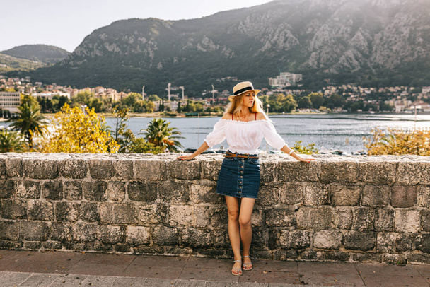 A hölgy Kotor régi falának erődítménye mellett áll Montenegróban. Unesco világörökség. Európa utazási oldala. Szabadság koncepció. Idegenforgalom az adriai tengerben. Szerbia történelme balkánok, erőd és kikötői épületek. - Fotó, kép