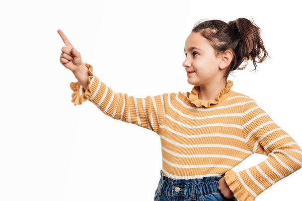 Girl pointing up and showing something while standing on isolated white background. - Foto, Bild