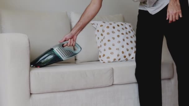 Lähikuva kädet Aasian mies puhdistus sohva pölynimurilla olohuoneessa kotona. - Materiaali, video