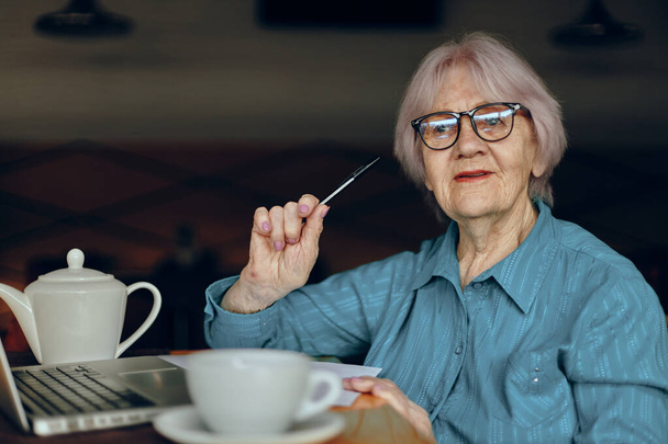 Portrait of an elderly woman in a cafe a cup of drink laptop Social networks unaltered - Fotó, kép