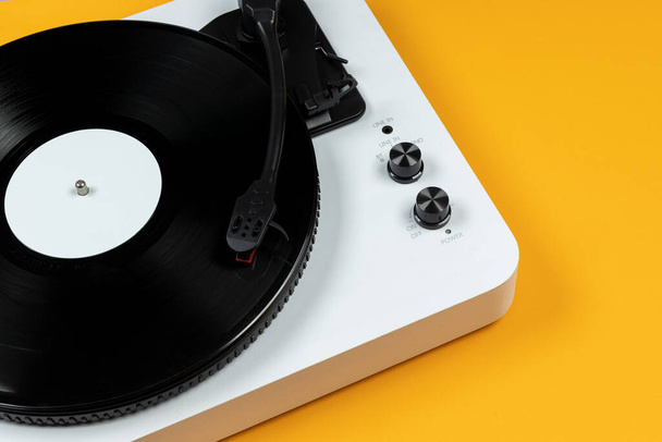 Otočný vinylový stůl s vinylovou deskou na žlutém pozadí. Moderní gramofonový přehrávač. Retro zvuková technologie pro přehrávání hudby - Fotografie, Obrázek