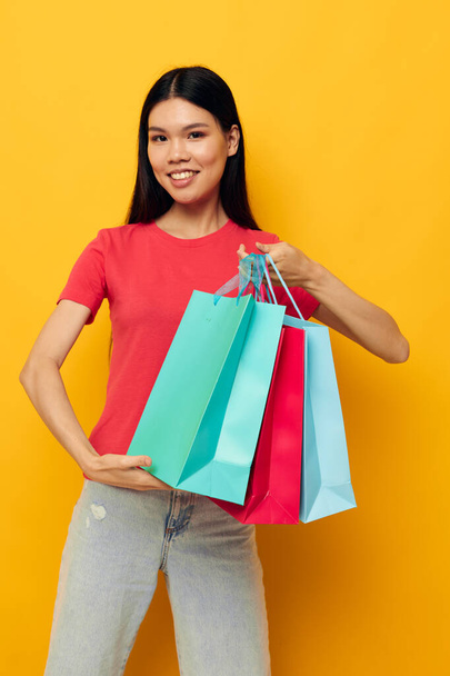 Portrait Asian beautiful young woman with colorful bags posing shopping fun studio model unaltered - Foto, imagen