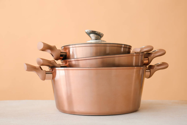 Shiny cooking pots on table against beige background - Photo, Image