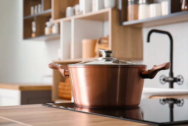 Glanzende kookpot op fornuis in lichte keuken - Foto, afbeelding