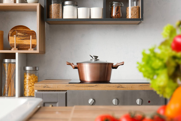 Shiny cooking pot on stove in modern kitchen - Fotó, kép
