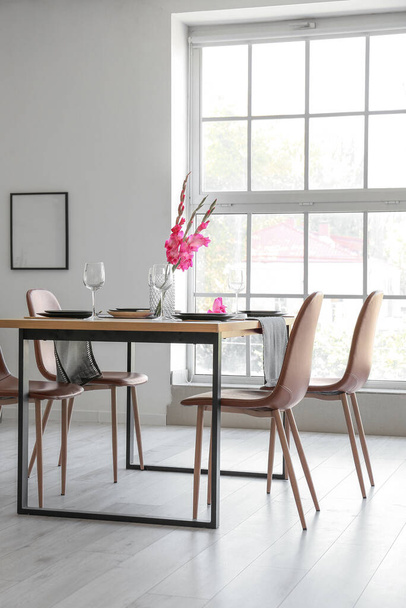 Interno della moderna sala luce con tavolo da pranzo servito e fiori di Gladiolo - Foto, immagini