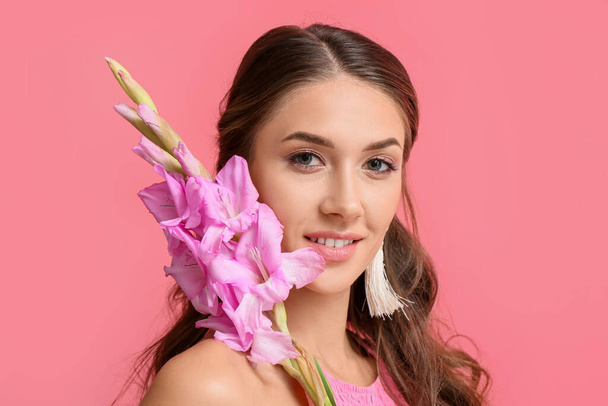Beautiful woman with Gladiolus flowers on color background - Photo, Image