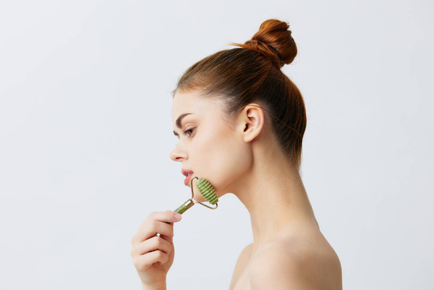 beautiful woman with  jade face massager on  isolated background. High quality photo - Φωτογραφία, εικόνα