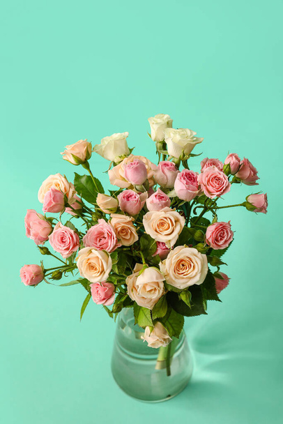 Glazen vaas met boeket van mooie kleine rozen op groene achtergrond - Foto, afbeelding