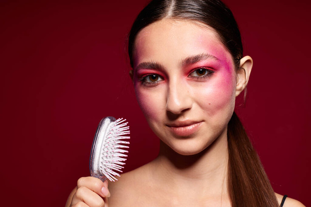 Retrato de hermosa mujer joven maquillaje emociones cosméticos cuidado del cabello rosa fondo inalterado - Foto, imagen