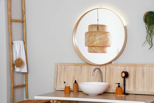 Tavolo con lavabo, accessori per il bagno e lampada vicino alla parete luminosa - Foto, immagini