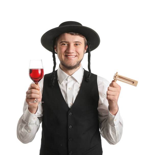 Joven judío con copa de vino y gragger para las vacaciones de Purim sobre fondo blanco - Foto, imagen