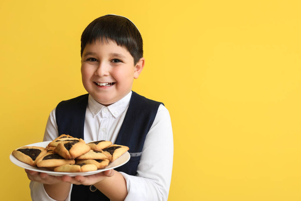 Petit garçon juif avec Hamantaschen savoureux pour les vacances Pourim sur fond de couleur - Photo, image