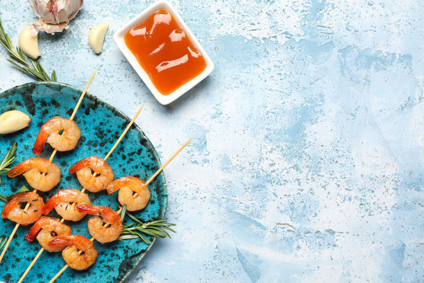 Plate with grilled shrimp skewers and sauce on blue background, closeup - Photo, Image