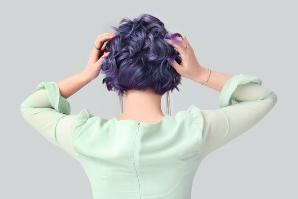 Hermosa mujer joven con pelo violeta sobre fondo claro, vista trasera. Muy Peri - el color del año 2022 - Foto, Imagen