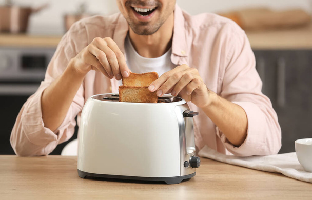Junger Mann macht leckere Toasts in Küche - Foto, Bild
