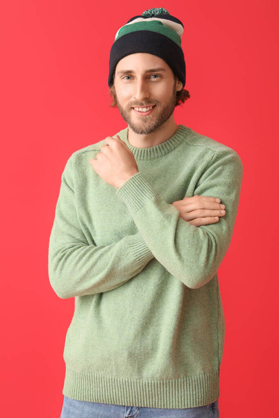 Handsome young man in knitted sweater on color background - Fotó, kép