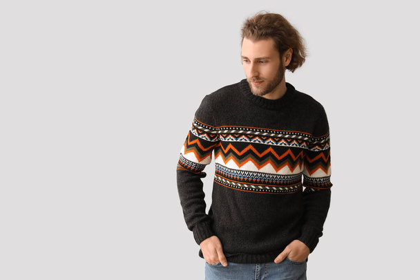 Jóképű fiatalember kötött pulóverben szürke alapon - Fotó, kép