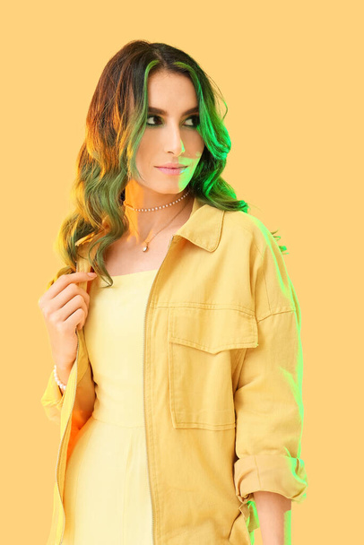 Mooie jonge vrouw met ongewone groene haren op kleur achtergrond - Foto, afbeelding