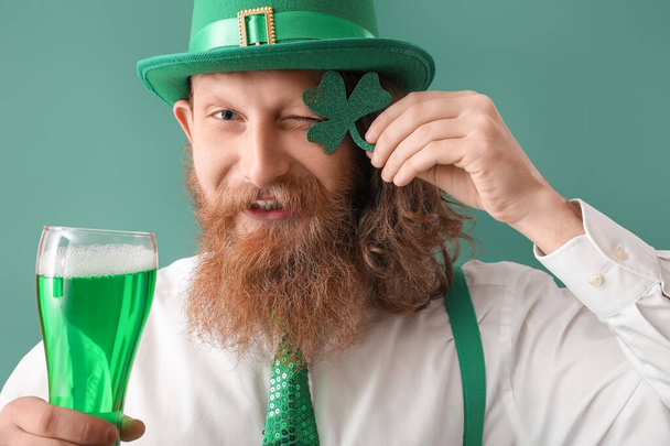 Χαρούμενος γενειοφόρος με τριφύλλι και ένα ποτήρι μπύρα σε πράσινο φόντο. Γιορτή του Αγίου Πατρικίου - Φωτογραφία, εικόνα