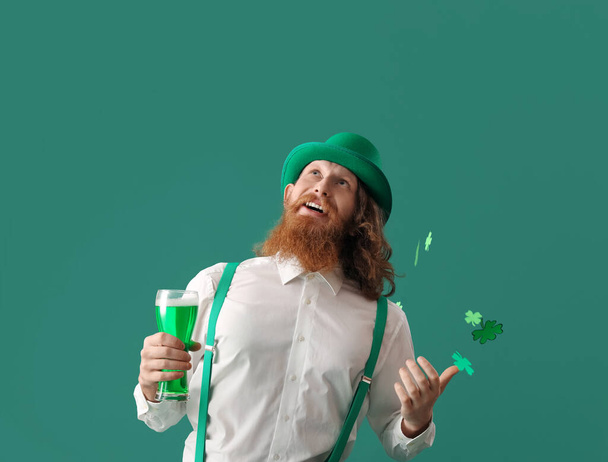 Щасливий бородатий чоловік зі склянкою пива та паперових конюшинок на зеленому тлі. День святого Патрика. - Фото, зображення