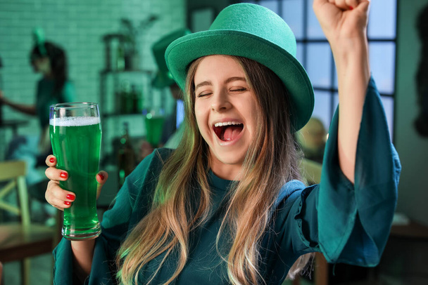 Happy young woman with glass of beer celebrating St. Patrick's Day in pub - Fotografie, Obrázek