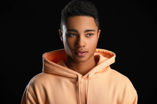 African-American teenage boy in hoodie on black background - 写真・画像