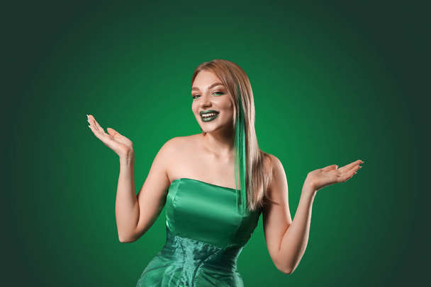 Beautiful young woman with unusual makeup for St. Patrick's Day on green background - Фото, зображення