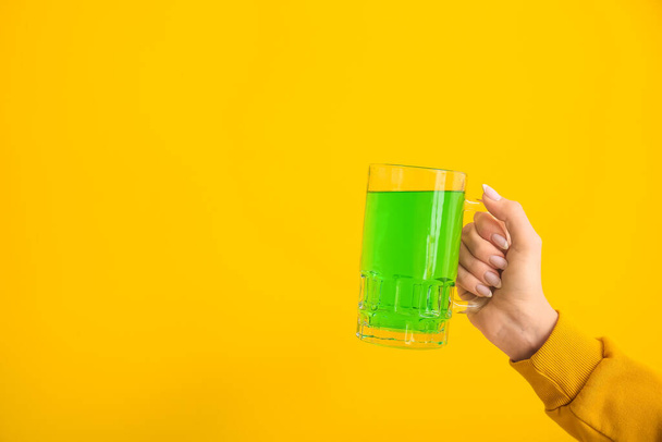 Junge Frau mit einem Glas grünen Bieres auf gelbem Hintergrund. St. Patrick 's Day Feier - Foto, Bild