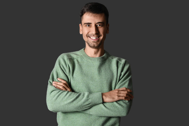 Handsome young man in knitted sweater on dark background - Photo, Image