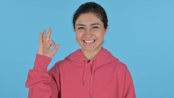 India chica mostrando Ok signo con dedo, fondo azul - Foto, imagen