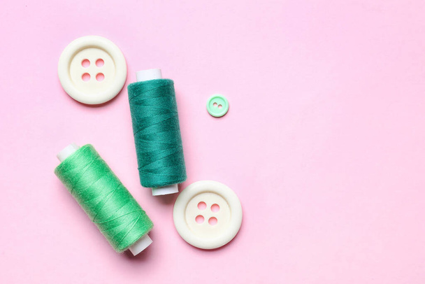 Hilos de coser con botones sobre fondo rosa - Foto, imagen
