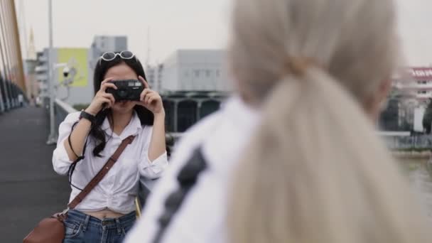 Asian lesbian couples enjoying traveling using film camera taking a photo. Two beautiful young women having fun in vacation time. - Πλάνα, βίντεο