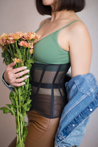 girl in a green top, corset holds flowers in her hands - Foto, Imagem