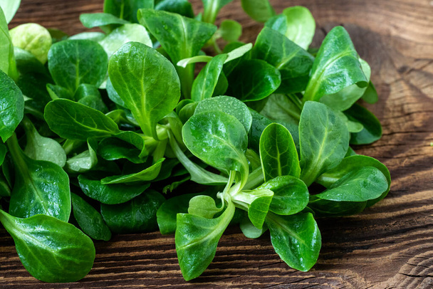 Листя зеленого салату (Vilerianella locusta). Свіжий салат з баранини кукурудзяний салат на сільському дерев'яному столі
 - Фото, зображення