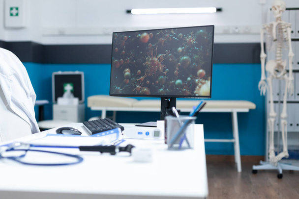空の病院オフィスを持っているコンピュータ上のテーブルの上にコロナウイルス細胞 - 写真・画像